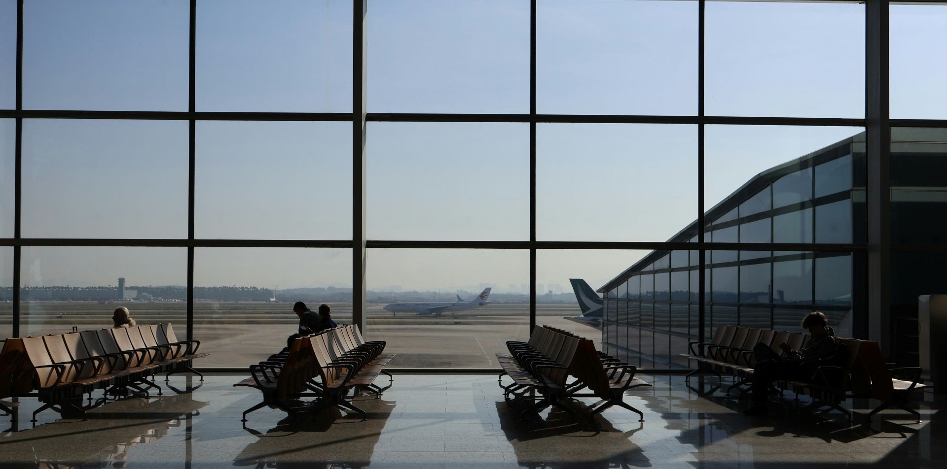 airport view from inside, people on chairs in airport
